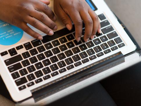 View of person's hands typing on a laptop