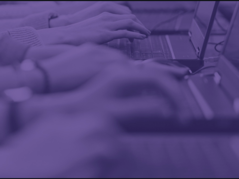 Purple-shaded image of hands typing on laptops