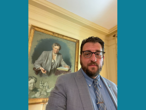 A photograph of Free Press Co-CEO Craig Aaron at the White House with a painted portrait of Eleanor Roosevelt behind him