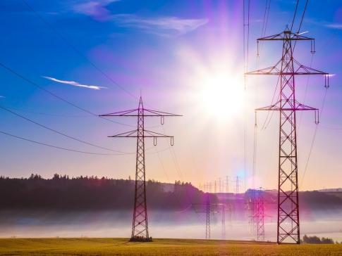 A photograph of powerlines with the bright sun behind them