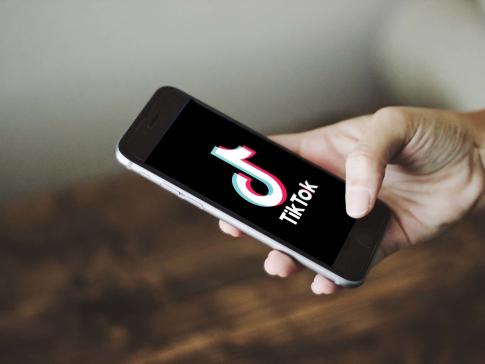 Hand holding a phone displaying the TikTok app