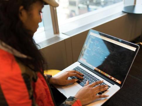 Woman with baseball cap typing on laptop