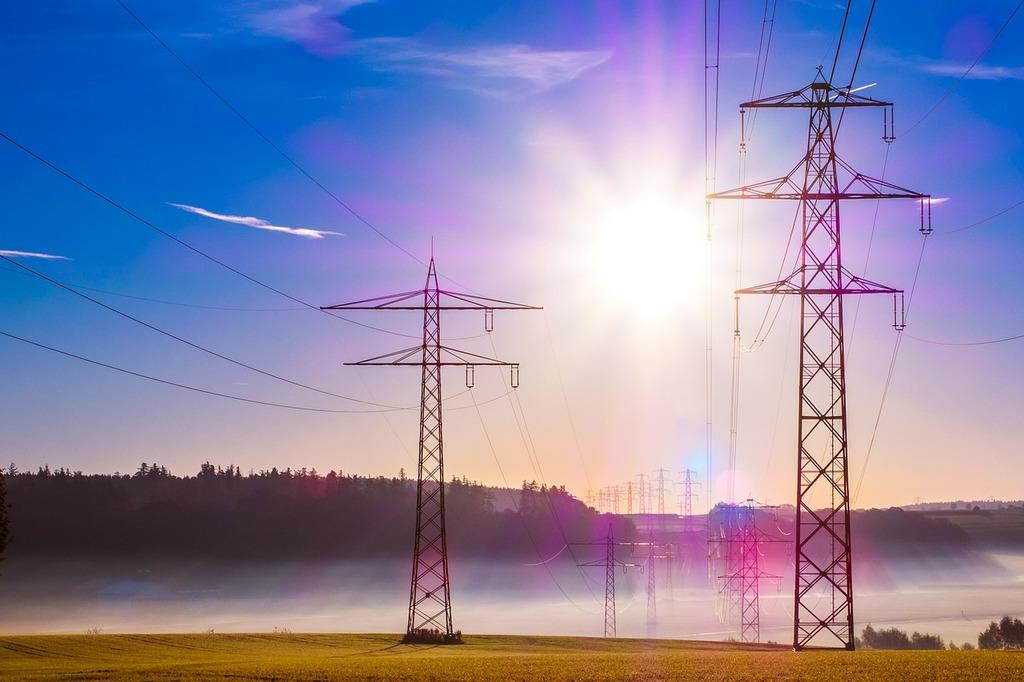 A photograph of powerlines with the bright sun behind them